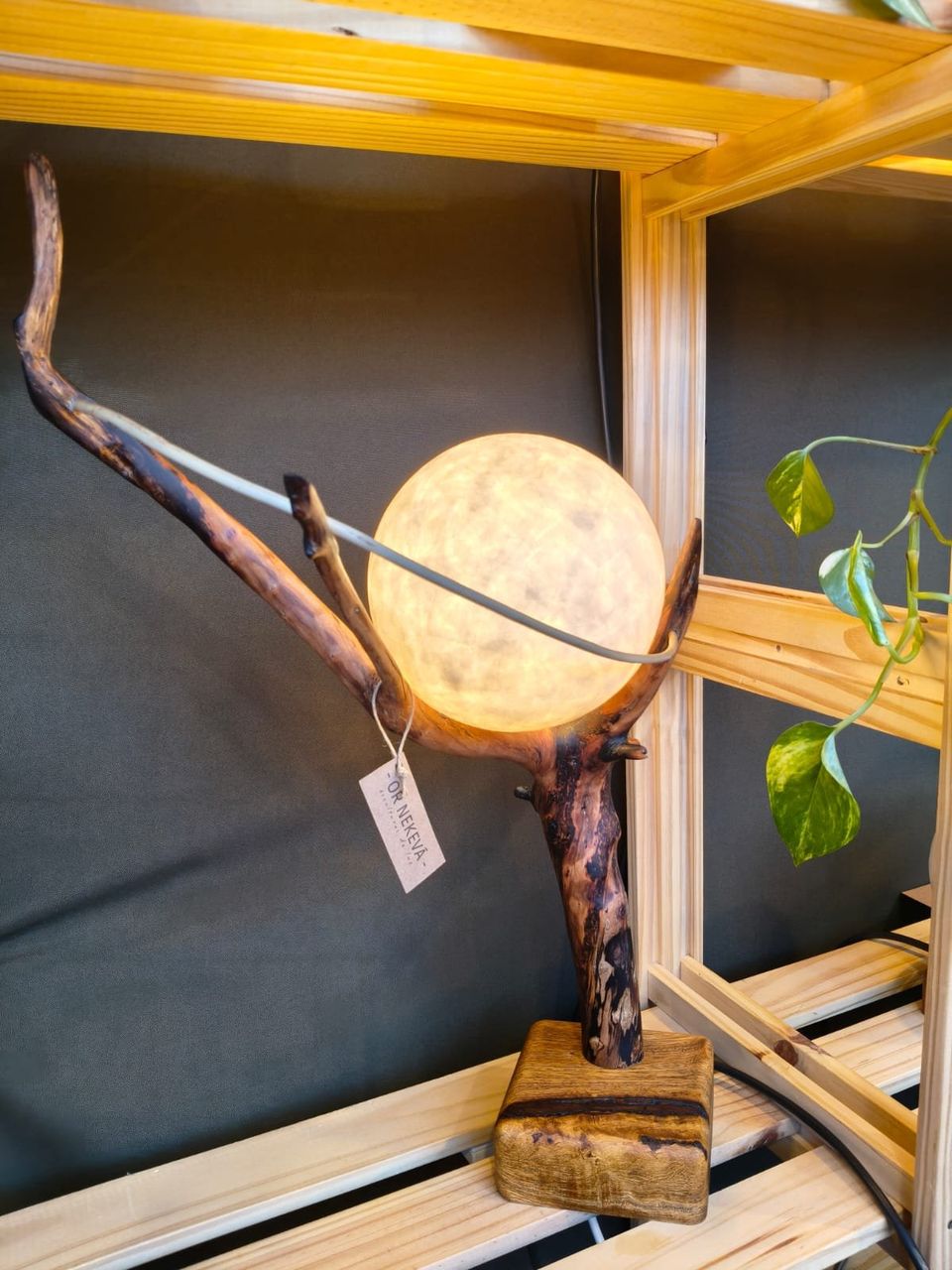 Luna: esfera de papel sostenida por una rama curva sobre base de madera