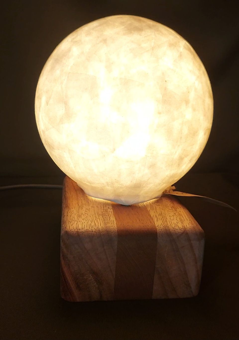 Esfera de papel encendida sobre una base cúbica de madera maciza