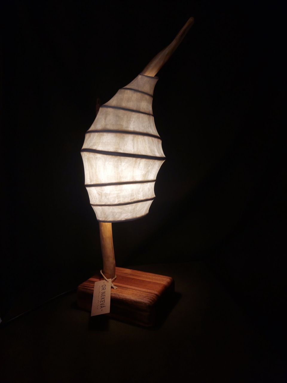 Lámpara de mesa con forma de hoja de papel nervada sobre base de madera